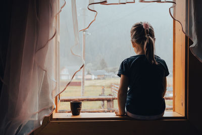 Rear view of woman looking through window