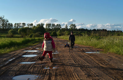 Two children playing on dirt road