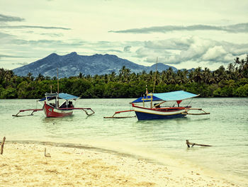 Boats moored in sea against mountains