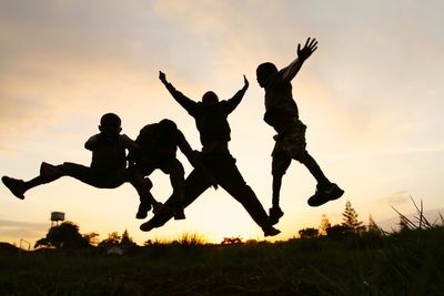 Low angle view of woman jumping at sunset