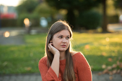 Young woman looking away while sitting outdoors