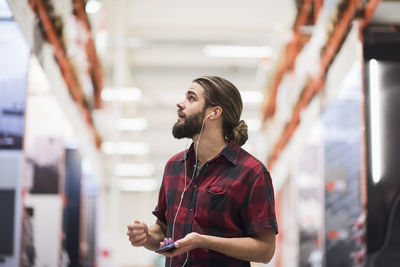 Customer looking up while listening music through smart phone at hardware store