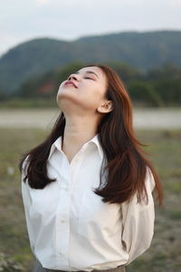 Portrait of young woman standing against wall