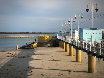 Pier on beach against sky