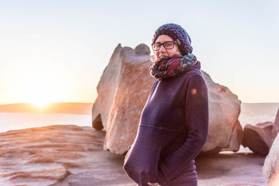 Portrait of woman standing against rock and sky