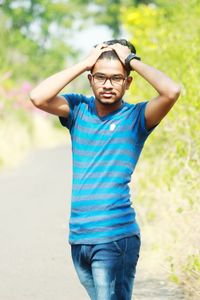 Portrait of young man with arms raised standing outdoors