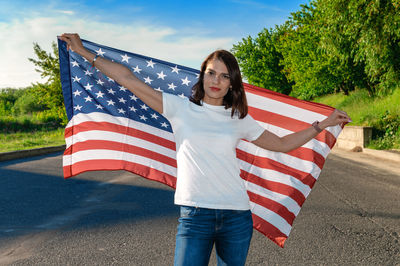 Portrait of smiling pretty young woman holding waving american flag. usa celebrate 4th of july. 