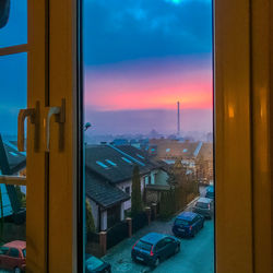 Cityscape against sky during sunset seen through window