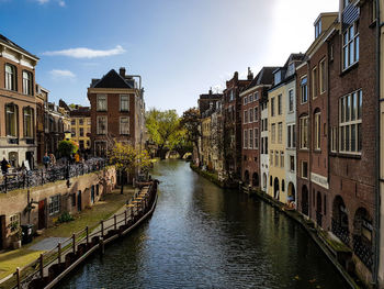 Canal amidst buildings in city against sky