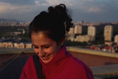 Close-up of smiling woman against cityscape