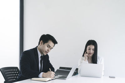 Young man using mobile phone while sitting on table
