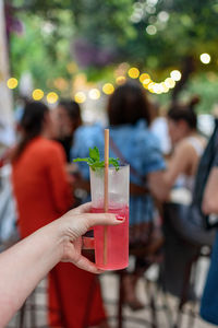 Personal perspective of woman holding cocktail glass with red cocktail