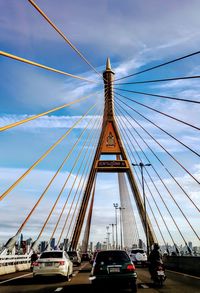 Low angle view of suspension bridge against cloudy sky