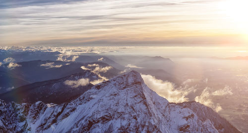 Aerial view of snowcapped mountains against sky during sunset