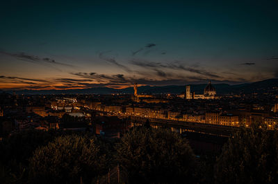 Illuminated city against sky at sunset