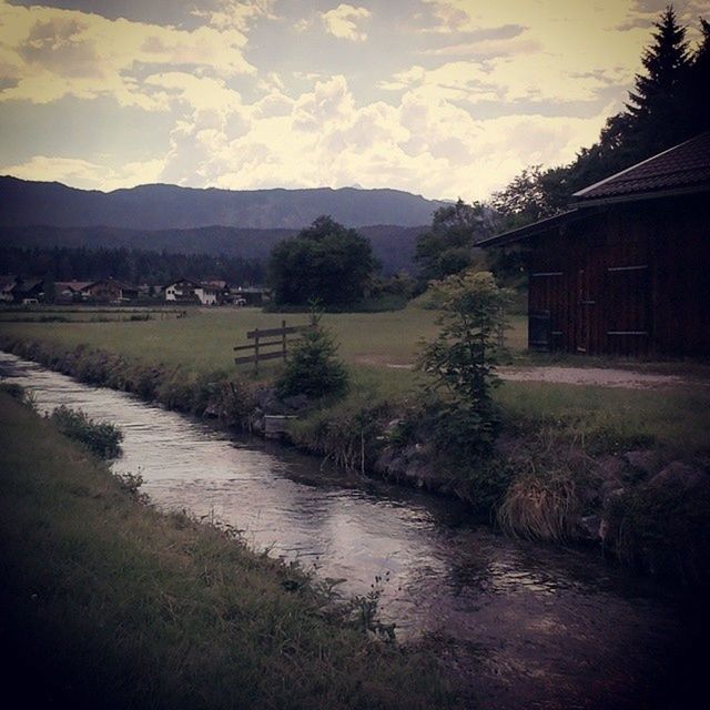 sky, building exterior, built structure, architecture, mountain, water, tree, house, cloud - sky, tranquil scene, tranquility, scenics, nature, beauty in nature, landscape, cloud, river, sunset, outdoors, grass