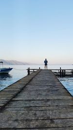 Man standing on pier over sea against sky