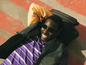Carefree young man wearing sunglasses while lying on floor during sunny day