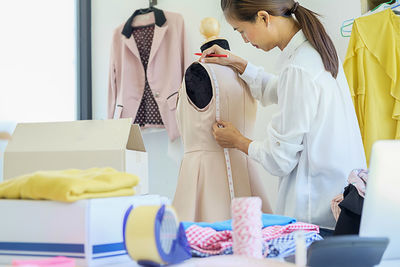 Fashion designer measuring dress on mannequin in office