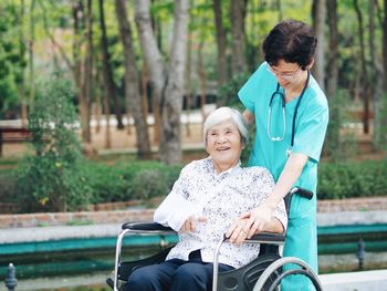 Nurse with female patient on wheelchair at park