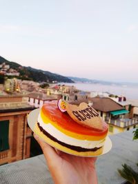 Close-up of hand holding ice cream against sky