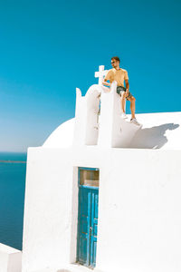 Low angle view of young woman standing against blue sky