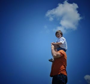 Low angle view of woman standing against blue sky