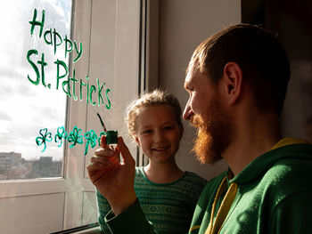 Drawing st. patrick's day father daughter painting green three-leaved shamrocks.stay home new normal