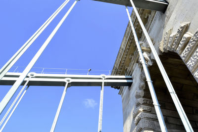 Low angle view of bridge against buildings against clear blue sky