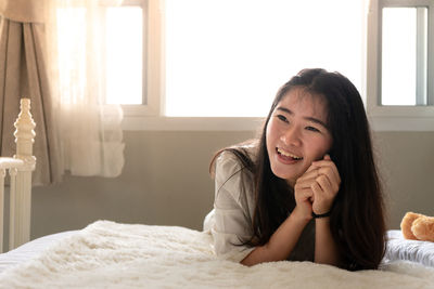 Portrait of young woman lying on bed