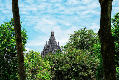 View of trees and building against cloudy sky