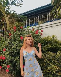 Portrait of smiling young woman standing against plants