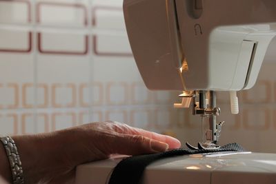 Cropped hand of woman sewing textile on machine
