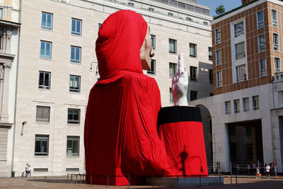 Woman standing by statue against buildings in city