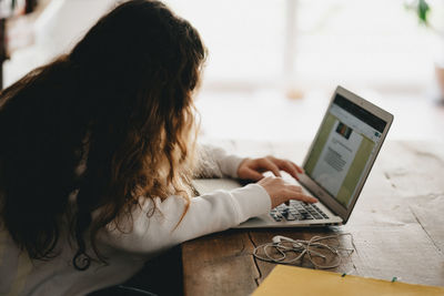 Rear view of woman using mobile phone at home