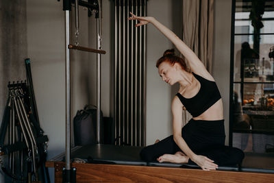 Side view of young woman with arms raised