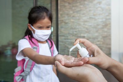 Cropped hands giving sanitizer to girl