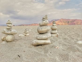 Stack of stones on sand against sky