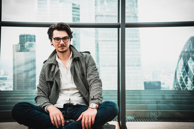 Portrait of young man sitting against window