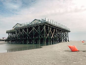 Pier on beach against sky