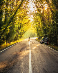 Rear view of man crossing the road in forest