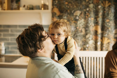 Mother kissing son on cheek at home