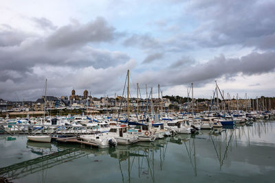 Sailboats moored at harbor against sky