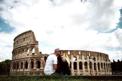Couple kissing while standing against coliseum