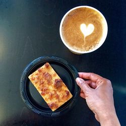 High angle view of hand reaching for dessert with coffee on table