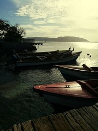 Boat moored at shore against sky during sunset