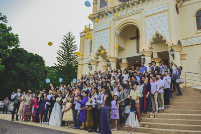 Newly married couple outside church with family and friends