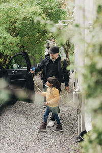 Man with daughter at electric car charging station