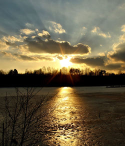 Sun shining over lake during sunset