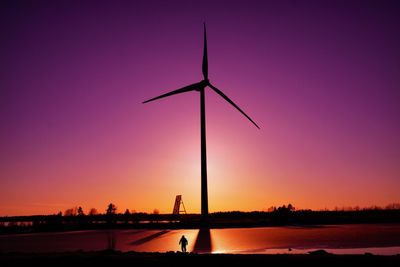 Silhouette windmills against sky during sunset